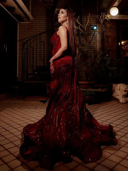 A full-length view of the stunning red sculpted gown. The long, dramatic trail and unique textured fabric make this a true work of art, perfect for a bride who wants a high-fashion look.