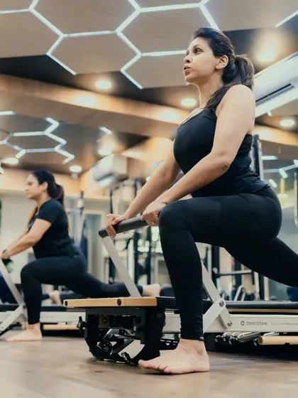 A classic Reformer lunge, this exercise is fundamental for building leg strength and improving hip flexibility. The clients demonstrate excellent form and control.