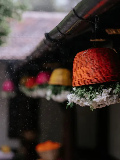 A close-up of the colorful hanging baskets adorned with flowers, with raindrops falling around them, creating a beautiful and atmospheric detail shot.