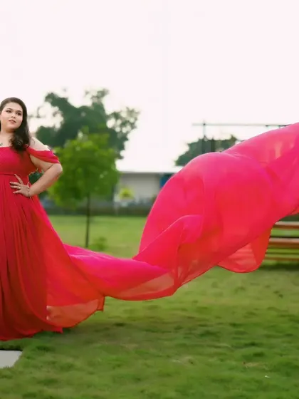 The flowing trail of this hot pink-red gown catches the light beautifully in this outdoor setting. It's a perfect choice for a vibrant and cheerful pre-wedding look.