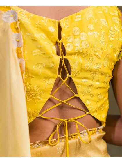 The back of this lime yellow blouse is designed with a modern corset-style tie-up, adding a contemporary twist to the traditional self-thread embroidery. It is a design that is beautiful from every angle.