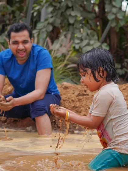 A father and child having a blast in the mud play area during our Holi festivities.