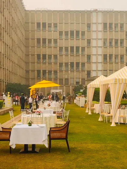 A wide shot of an outdoor brunch setup, with rows of elegant tented seating areas on a lush green lawn, creating a chic and comfortable space for guests.