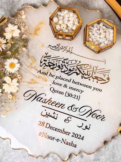 This elegant white and gold resin tray is perfect for a classic and timeless wedding theme. It features beautiful branch-style handles, delicate daisy accents, and is personalized with the couple's names and a Quranic verse in stunning calligraphy.