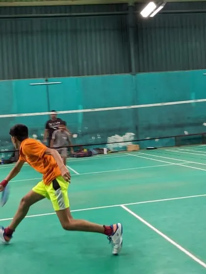 An action shot of a junior player moving quickly across the court during a badminton drill. Our training emphasizes agility and quick reflexes.