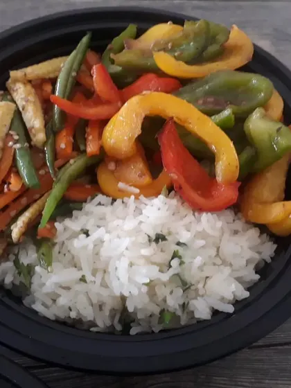 A Jain-friendly rice bowl prepared with no onion, garlic, or chili, served with colourful bell peppers and baby corn.