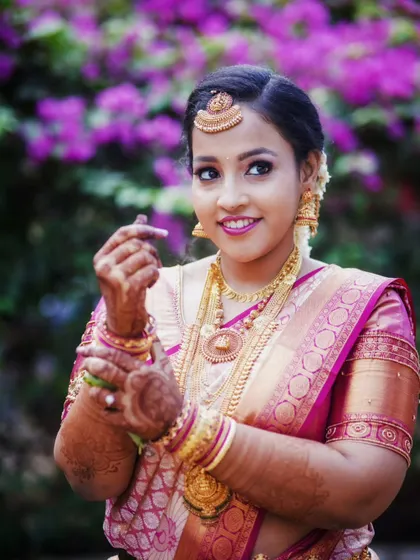 A lovely bridal portrait showing the intricate details of her temple jewelry and the rich silk of her pink saree.