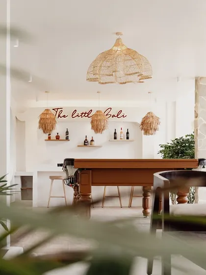 Tucked away from the main living area, this cozy corner with a pool table and bar is called 'The Little Bali'. It's a perfect spot for intimate gatherings, with rattan pendant lights and simple wooden stools enhancing the relaxed, tropical vibe.