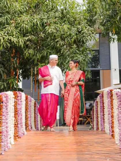 The couple walks across a flower-adorned bridge, a beautiful metaphor for their journey together. This shot captures the romance and scenic beauty of their Marathi wedding venue.