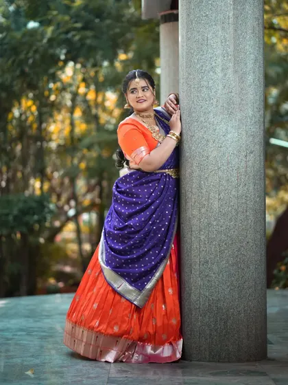 A candid moment in a custom orange and blue half saree, celebrating the warmth and happiness of Navaratri.