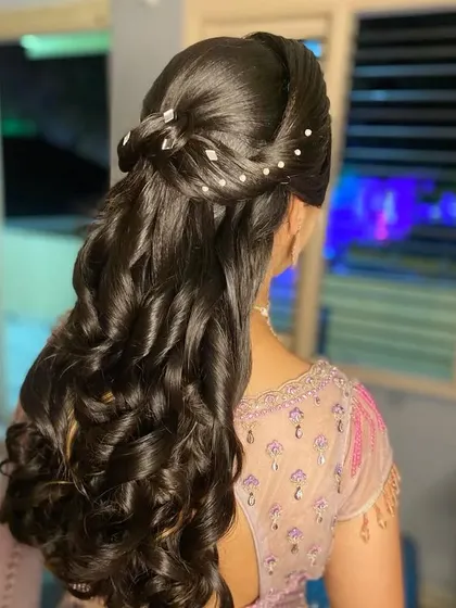 A high-fashion half-up style with a sculpted top, pearl accents, and flowing curls.