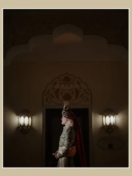 A dramatic portrait of the groom at his Jaipur wedding. The low-light and architectural details create a moody and regal image, highlighting his traditional attire.