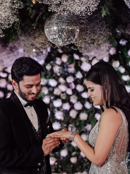 The moment of commitment. A close-up of the groom placing the ring on the bride's finger during their glamorous engagement party.