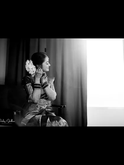 A beautifully composed black and white shot of the bride getting ready by a window.
