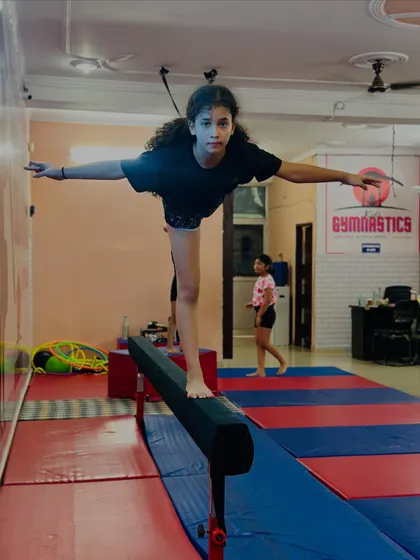 Another angle of the balance beam routine, showing the student maintaining her balance with arms outstretched. Each pose is practiced until it is flawless.