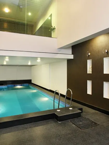 An indoor pool within the Courtyard Home. The space is located adjacent to the central courtyard, with a glass-railed balcony from the upper floor overlooking it, enhancing the home's open and connected feel.