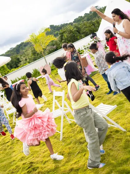 Kids playing a lively game of musical chairs on the lawn, led by an event host. Organized games are a great way to ensure all the children are included and having fun.