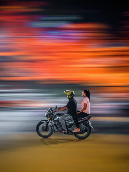 A couple on a motorcycle is captured with a skillful panning shot, creating a beautiful blur of motion and color in the background. This image perfectly freezes the action while conveying a sense of speed and journey.