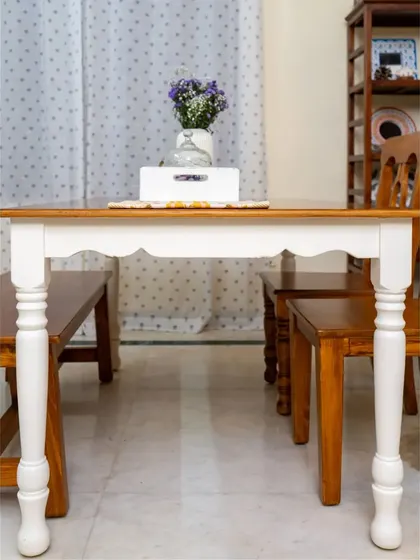 A beautiful dining table with a scalloped apron and classic turned legs, finished in a two-tone style.