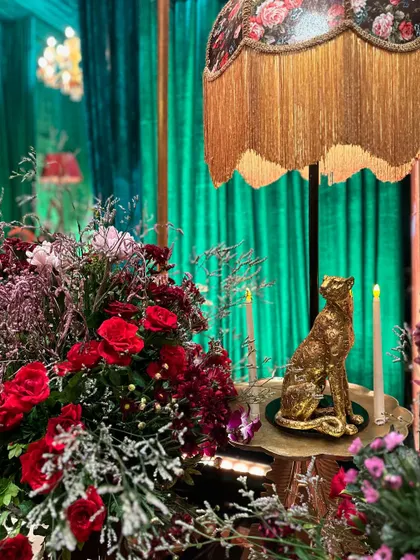 A metal leopard sculpture adds a touch of exotic glamour to this turquoise-themed musical night, complemented by red roses and a vintage lamp.