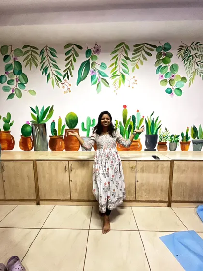 The completed potted plant mural, with me standing in front to show the scale. The design spans the length of the wall, creating a cheerful and green horizon.
