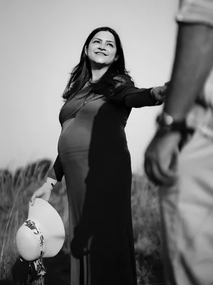 A beautiful black and white "follow me" shot, where the mom-to-be looks back with a bright, happy expression.