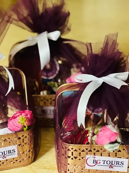 Corporate Diwali hampers for 'BG Tours & Travels', wrapped in rich purple tulle with white ribbons, ready for delivery.