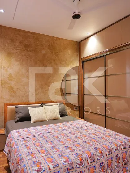 A cozy bedroom with a textured brown accent wall and a sliding wardrobe with mirrored panels. The design is warm and inviting, with pendant lights adding a modern touch.