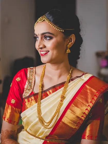 A classic South Indian bridal look with an off-white and red silk saree. The beauty of this ensemble lies in its simplicity and the perfect fit of the custom-designed blouse.