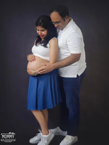 A tender moment between an expecting couple. The way he looks at her and they both gently hold the baby bump shows all the love and anticipation they share.