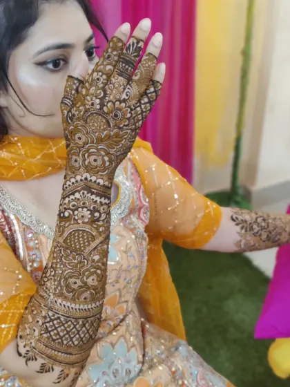 A lovely pose showing off a detailed bridal henna design on one arm. The pattern includes traditional elements like paisleys and intricate line work.