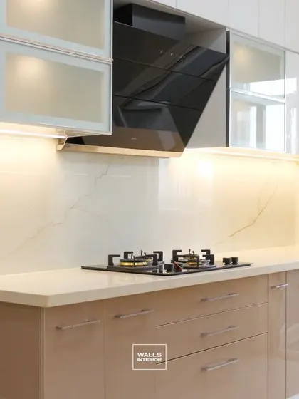 A classic and elegant kitchen design with glossy beige base cabinets and white overhead units with frosted glass. The warm under-cabinet lighting creates a welcoming ambiance.
