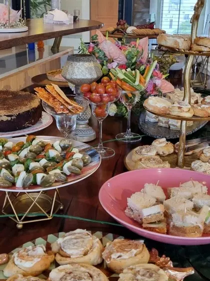 A high tea setup featuring cinnamon rolls, caprese skewers, and finger sandwiches. This spread is perfect for corporate gatherings or celebratory brunches, offering both sweet and savory options.