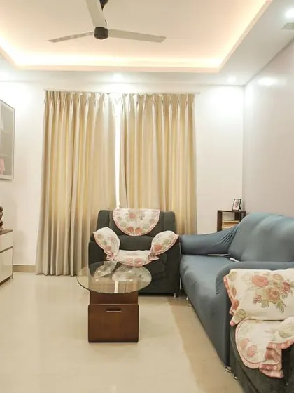A comfortable living room setup with a blue sofa and a custom TV unit. The marble back panel and wood-toned console create a balanced and stylish look.
