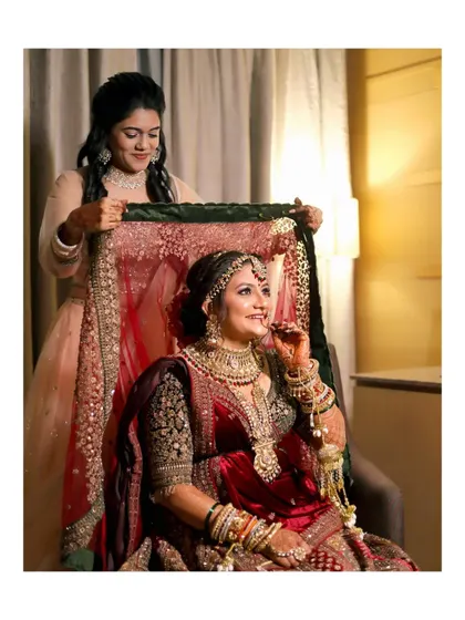 Another angle of the bridesmaid helping with the veil, capturing the bride's elegant profile and happy expression.