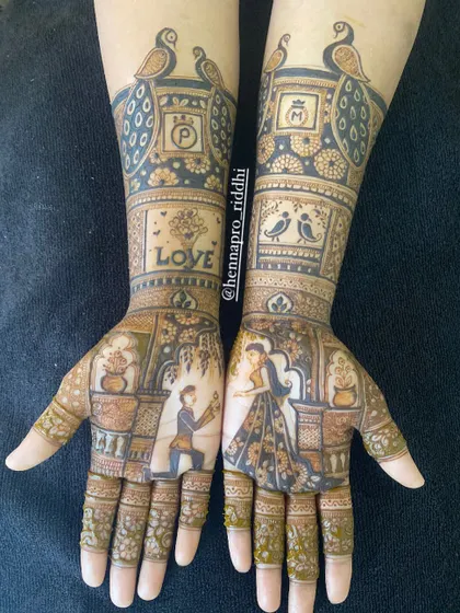 Another take on a proposal-themed engagement henna. This design uses color and shading to make the couple's portrait pop, surrounded by classic motifs like peacocks and the word "LOVE".