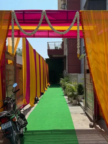 An entrance walkway created with colorful drapes and a green carpet, leading guests into the venue.