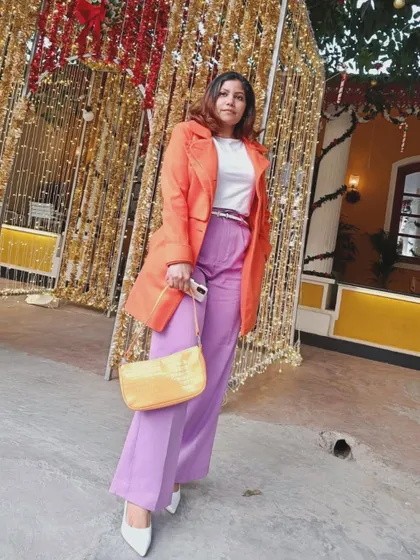 Posing in my colorful winter outfit against a golden, festive backdrop.