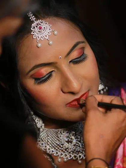A behind-the-scenes moment of a bride getting her final makeup touches, a key part of the getting-ready process.