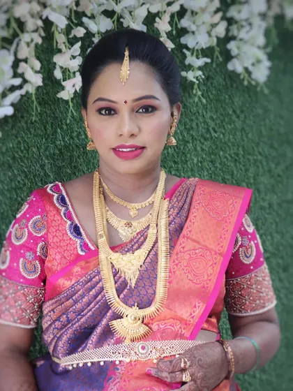 A lovely traditional look for a baby shower. The makeup is soft and glowing, with a simple gold jewelry set that perfectly complements her pink and purple silk saree.