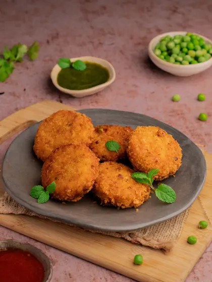 A plate of crispy vegetable patties served with green chutney. The simple, clean styling highlights the golden texture of the patties, making them look like a perfect evening snack.