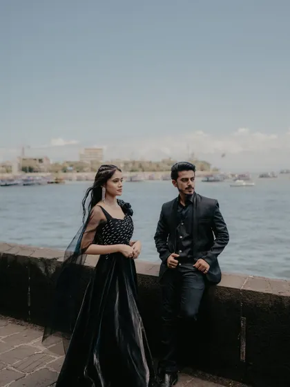 A stylish, posed shot of the couple by the sea wall. Their confident and relaxed postures give this photo a modern and fashionable feel.
