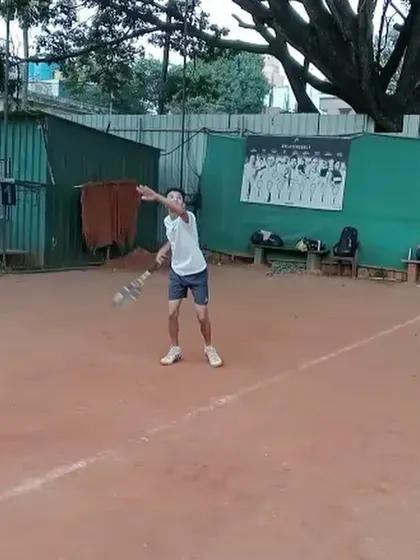 A young player warming up his serve. Proper warm-up routines are essential for performance and injury prevention, a key part of our training.
