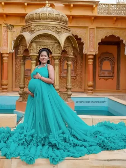 A solo shot of the expectant mother looking radiant by the water. The flowing trail of the gown adds a touch of drama and elegance to the photograph.