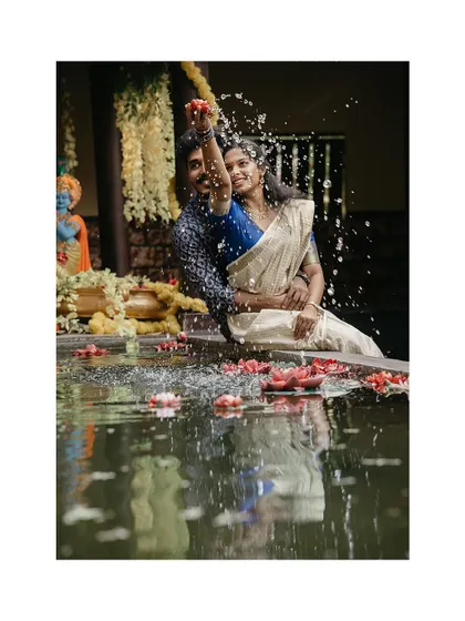 A playful moment with a couple splashing water from a traditional pond.