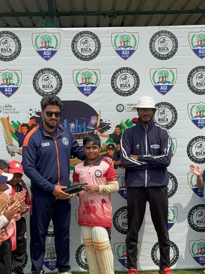 A young player is awarded for his performance, surrounded by his applauding teammates.