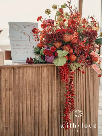 The bar at the tropical beach event, decorated with a cascade of red flowers and chilies.