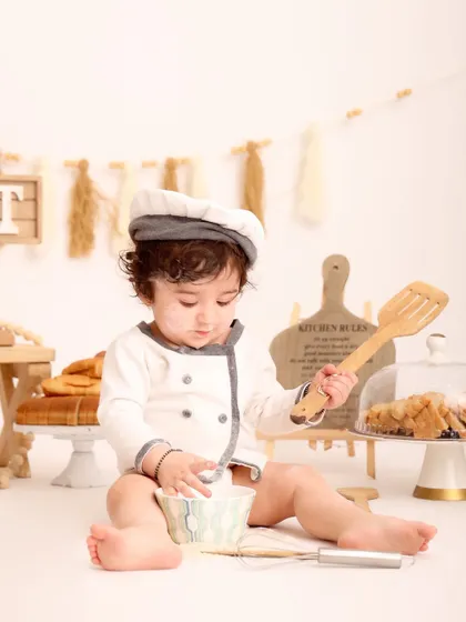 Getting serious about baking. This little chef is focused on mixing ingredients in a bowl, a candid moment that shows the fun and imaginative play of the session.
