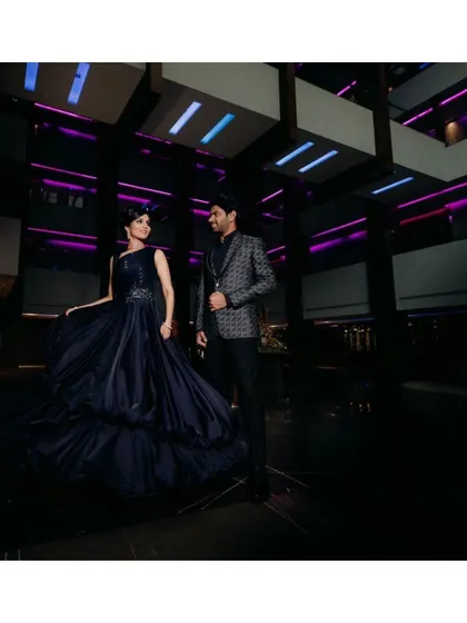 A dramatic, wide-angle shot capturing the couple at their cocktail party. The bride's bold makeup and flowing gown create a powerful and glamorous statement.