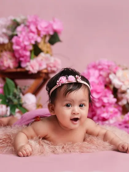 A beautiful tummy time portrait. Her curious expression and the soft pink surroundings create a gentle and lovely image.